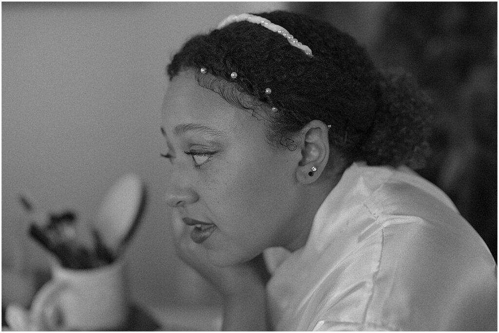 A bride applies makeup in a. mirror