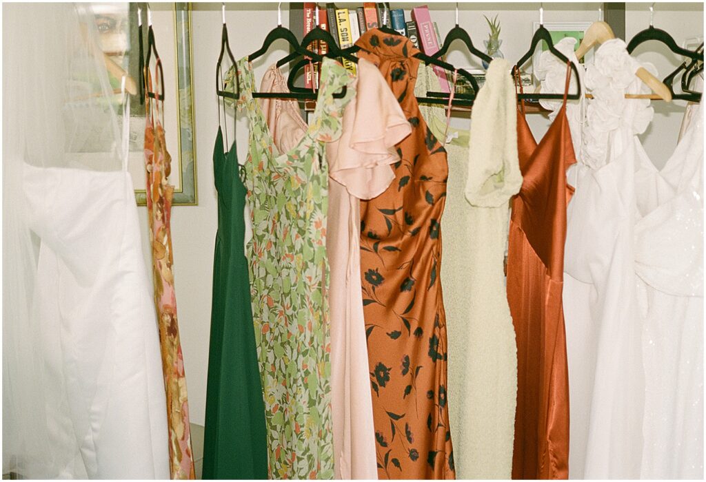 A wedding gown hangs beside colorful bridesmaids dresses.