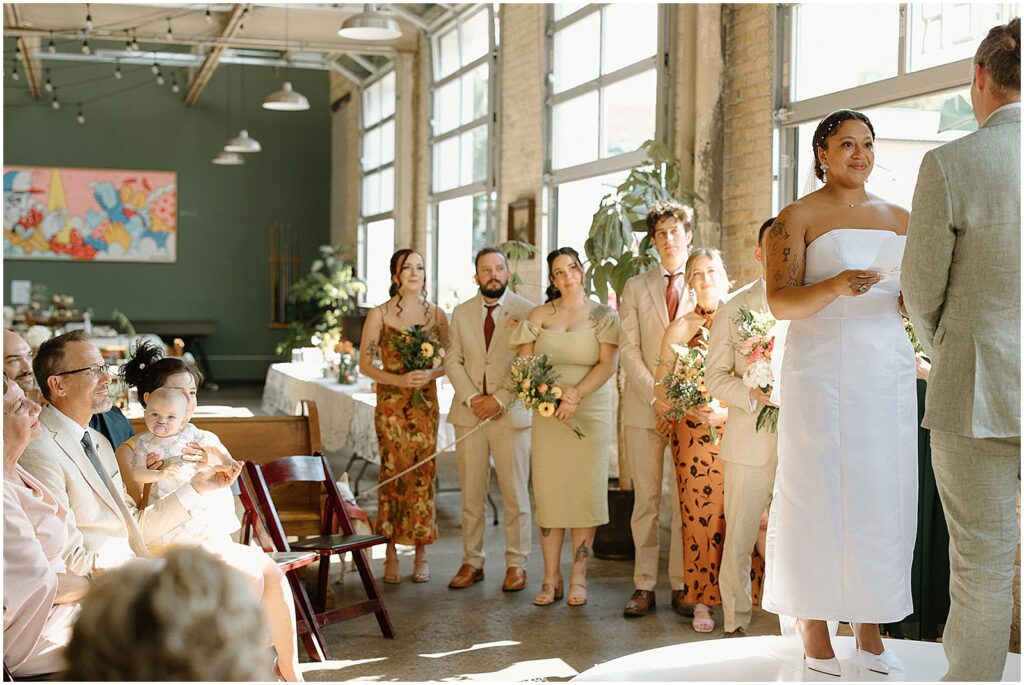 A bridal party smiles as they listen to a wedding ceremony.