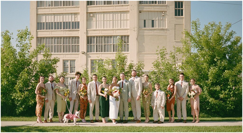 A bride and groom pose with their wedding parties in front of a building in Bay View Milwaukee.