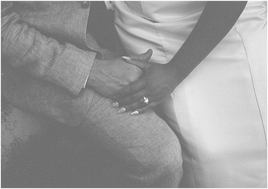 A bride holds hands with a groom in black and white film wedding photography.