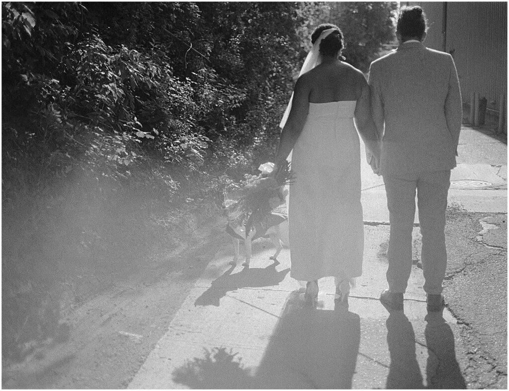 A bride and groom hold hands and walk down a Milwaukee sidewalk.