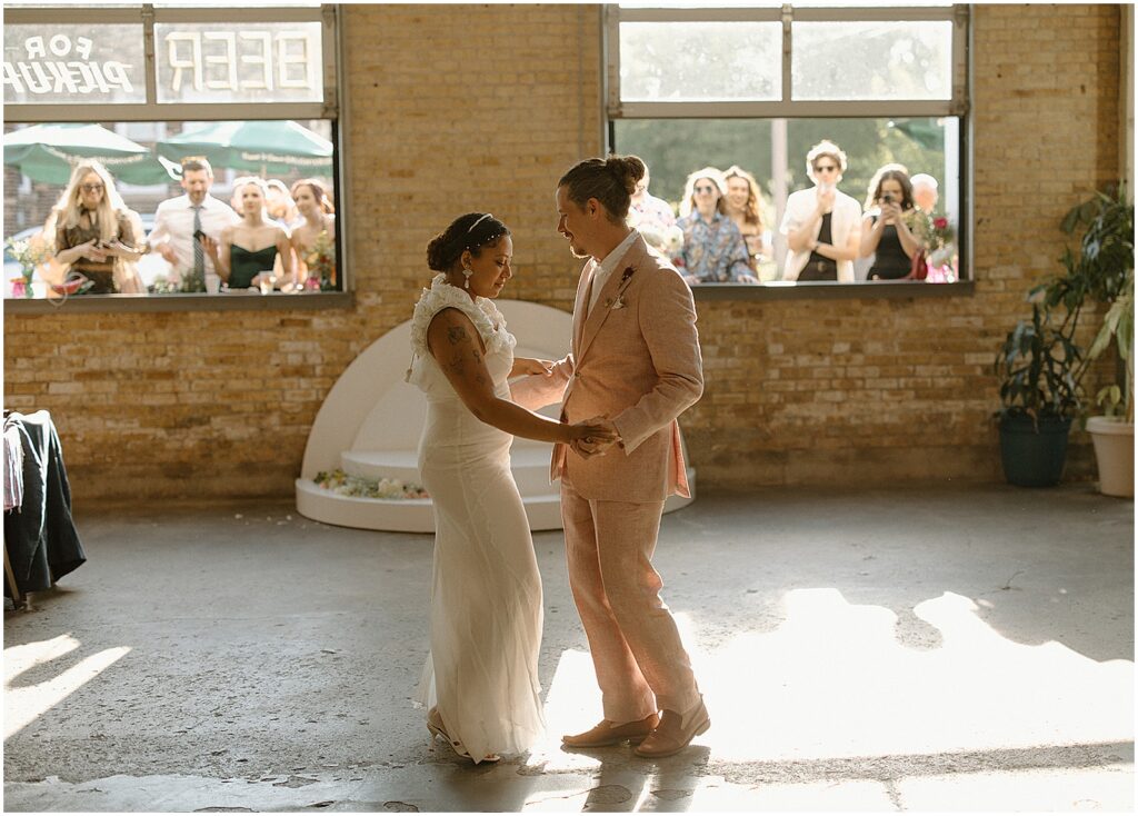 A bride and groom share their first dance in the taproom at Enlightened Brewing Company.