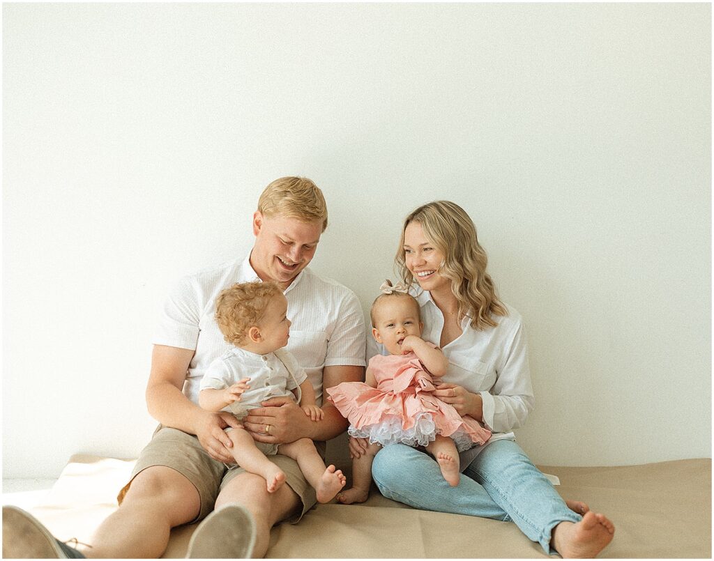 A mom and dad sit in a Milwaukee photography studio holding their twin babies.