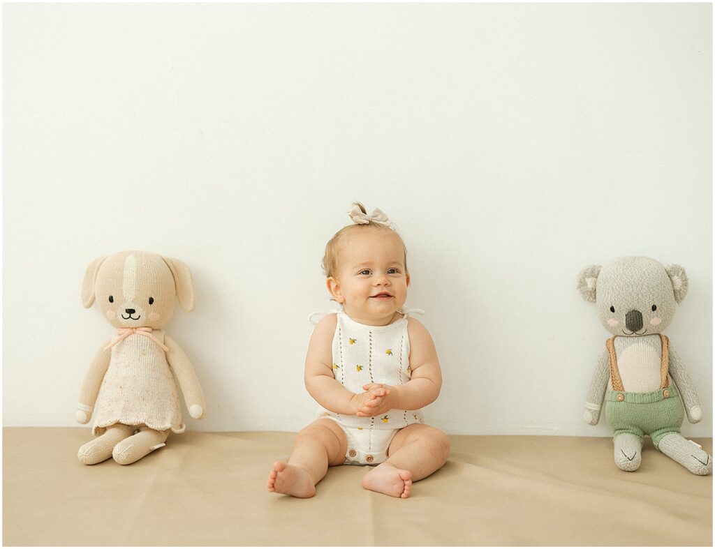 A baby poses between stuffed animals at a first birthday photoshoot in Milwaukee.