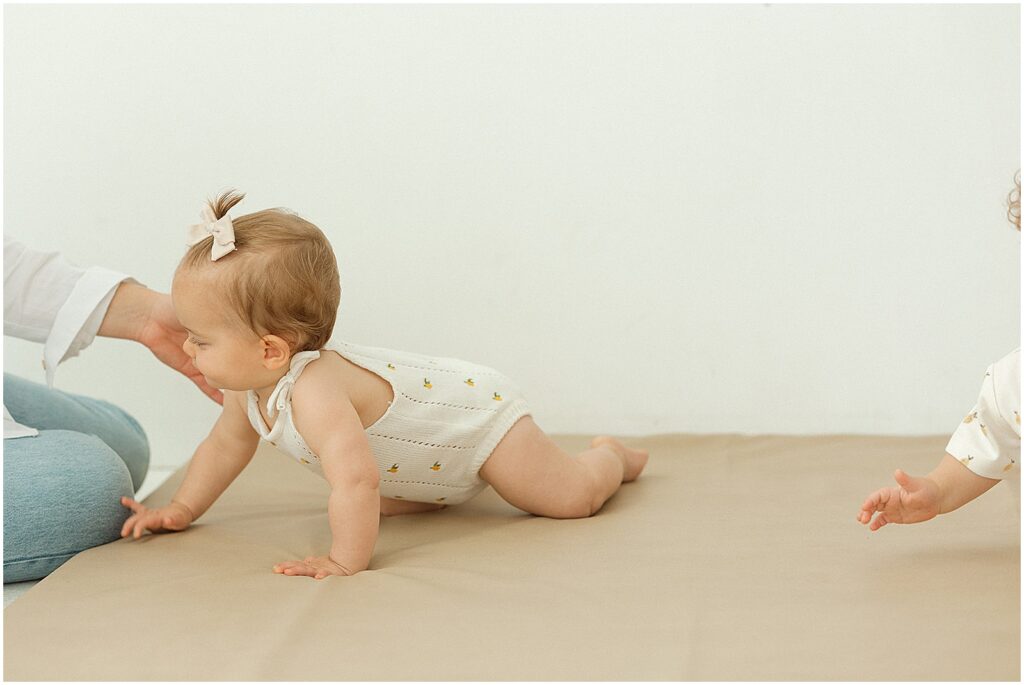 A baby crawls between parents during a Milwaukee family photography session.