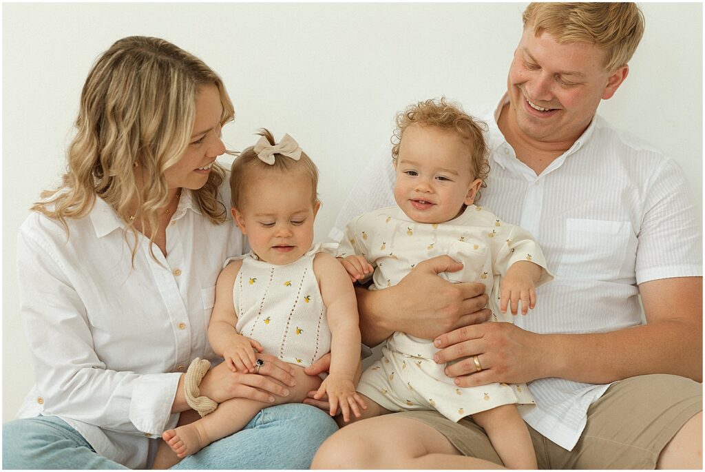 A mother and father cuddle their twins while a Milwaukee family photographer takes their picture.