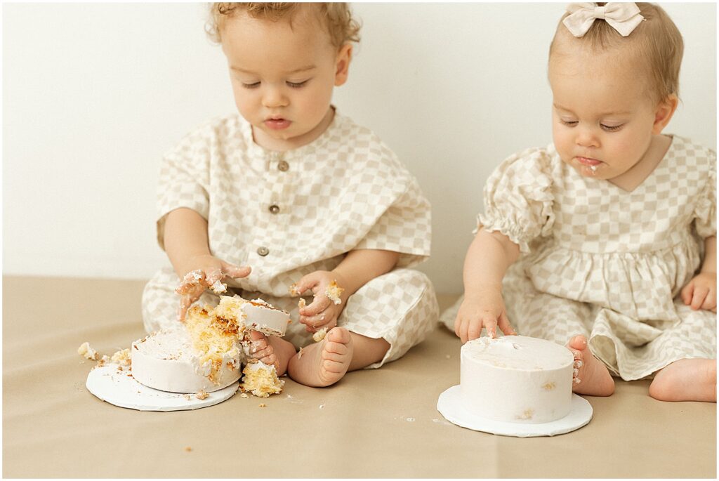 Twin babies smash cakes with their hands.