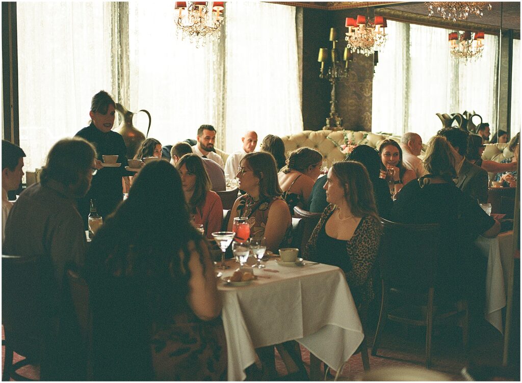 A waiter speaks to wedding guests at their reception tables.