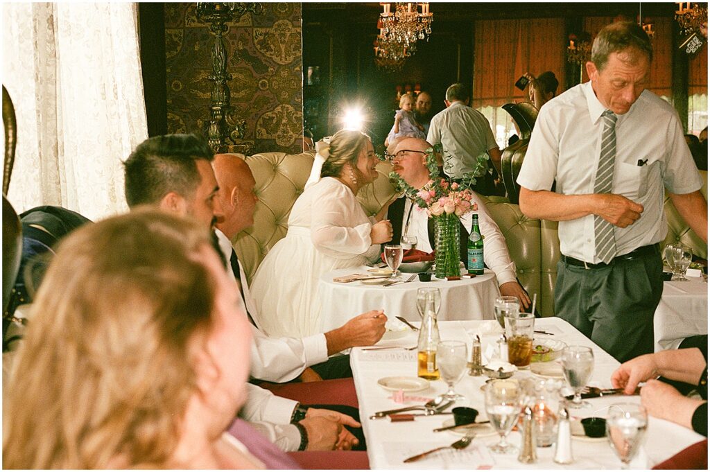 A bride and groom kiss in a candid wedding photo on film.