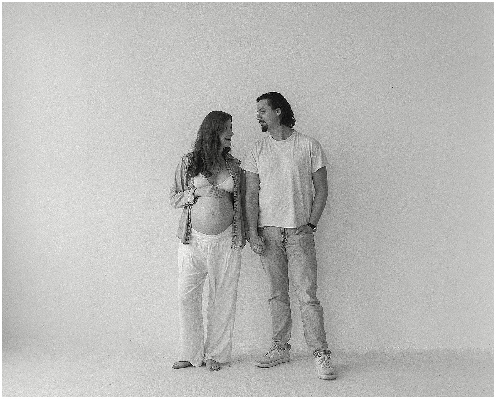 A man and woman pose in a studio for a Milwaukee maternity photographer.