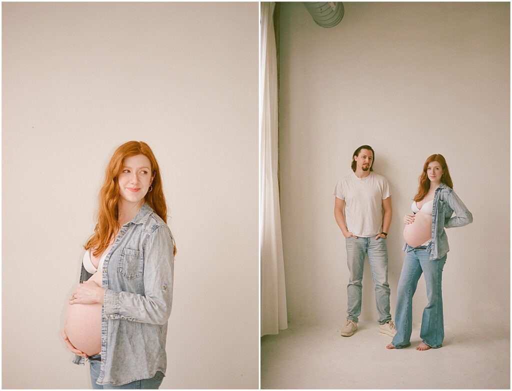 A man and woman stand in the corner of a photography studio holding hands during a maternity photography session.