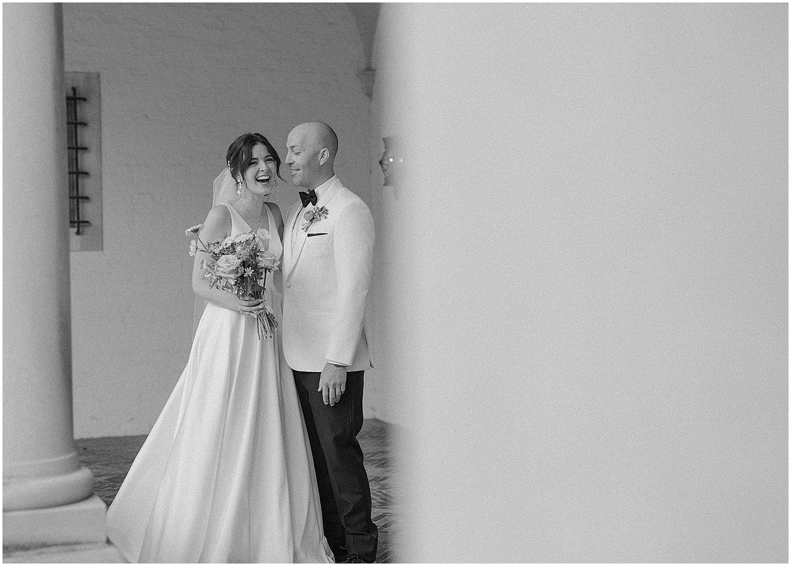 A bride and groom laugh during their first look in the courtyard at an art museum Milwaukee wedding.