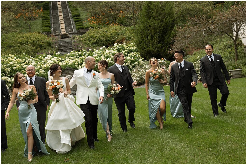 A bride and groom walk with their wedding party through the garden at their Villa Terrace Milwaukee wedding.