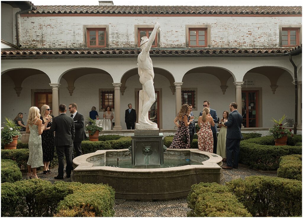 Wedding guests walk around a Milwaukee wedding venue courtyard during cocktail hour.