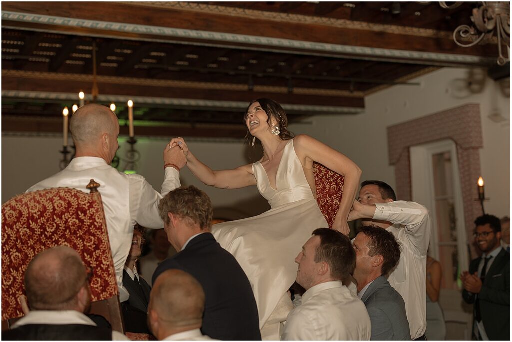 Guests lift a bride and groom for the horah.