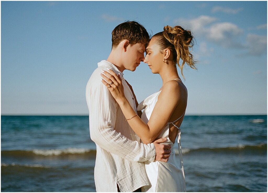 A man and woman in wedding attire stand on Atwater Beach during an elopement photo session.