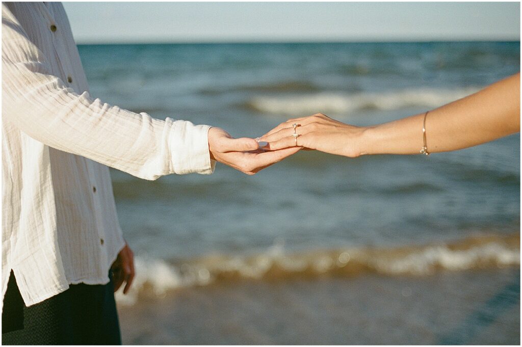 A bride and groom reach their hands towards each other during an elopement photography session at Atwater Beach.