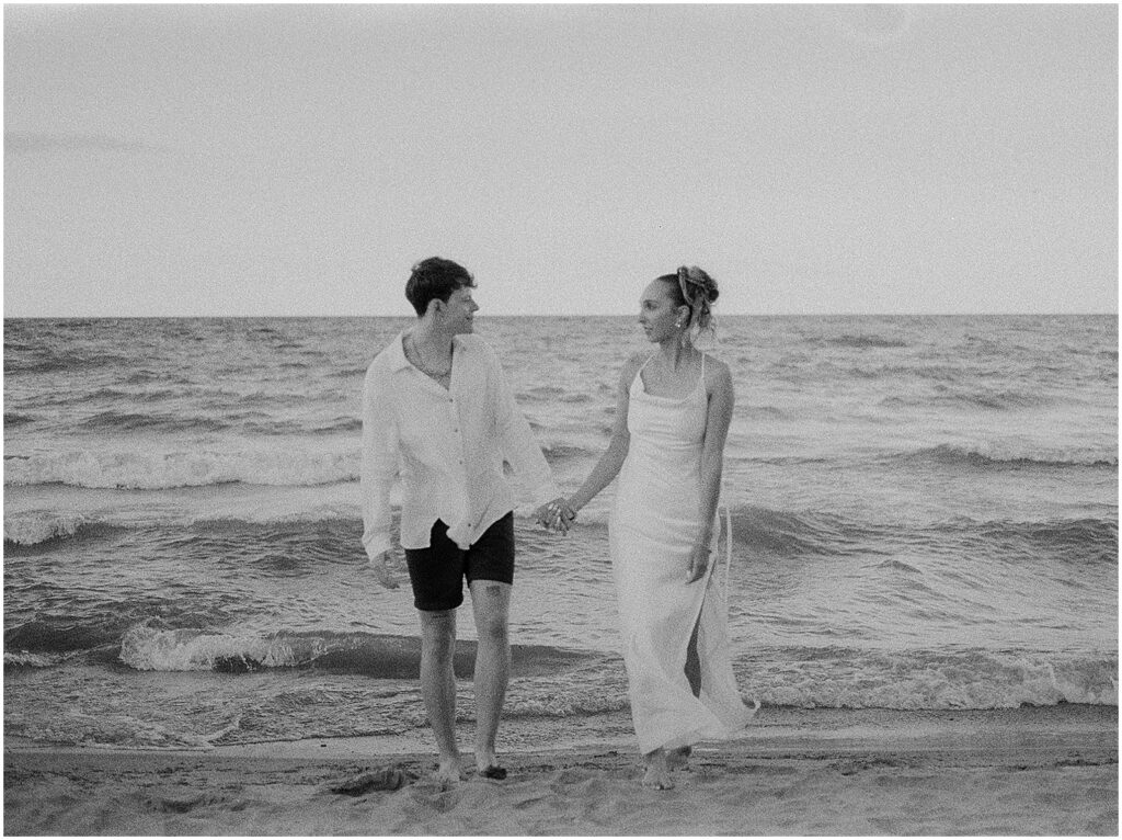 A bride and groom walk towards a Milwaukee elopement photographer holding hands.