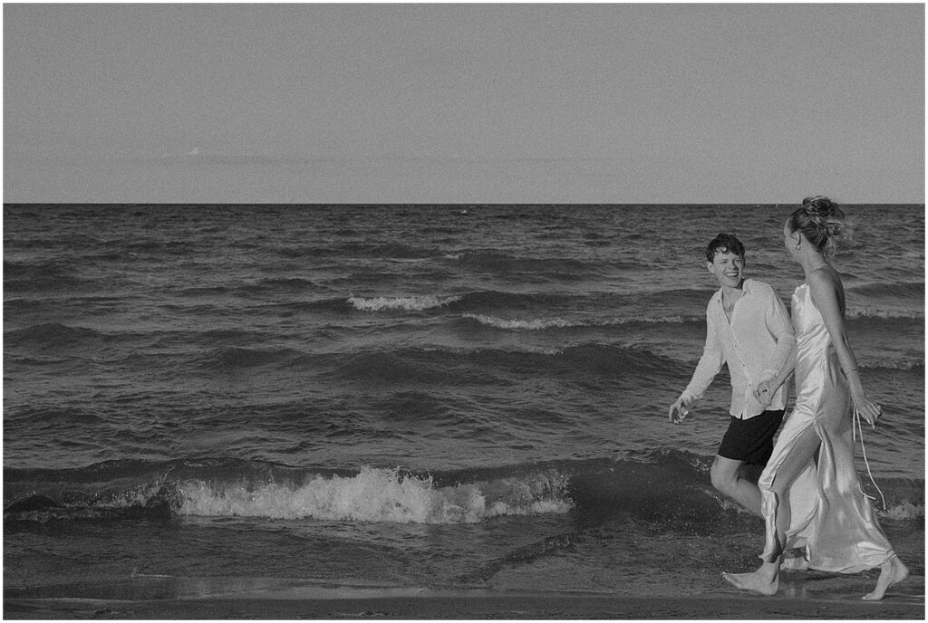 A bride and groom run laughing down a beach in Milwaukee elopement photos.