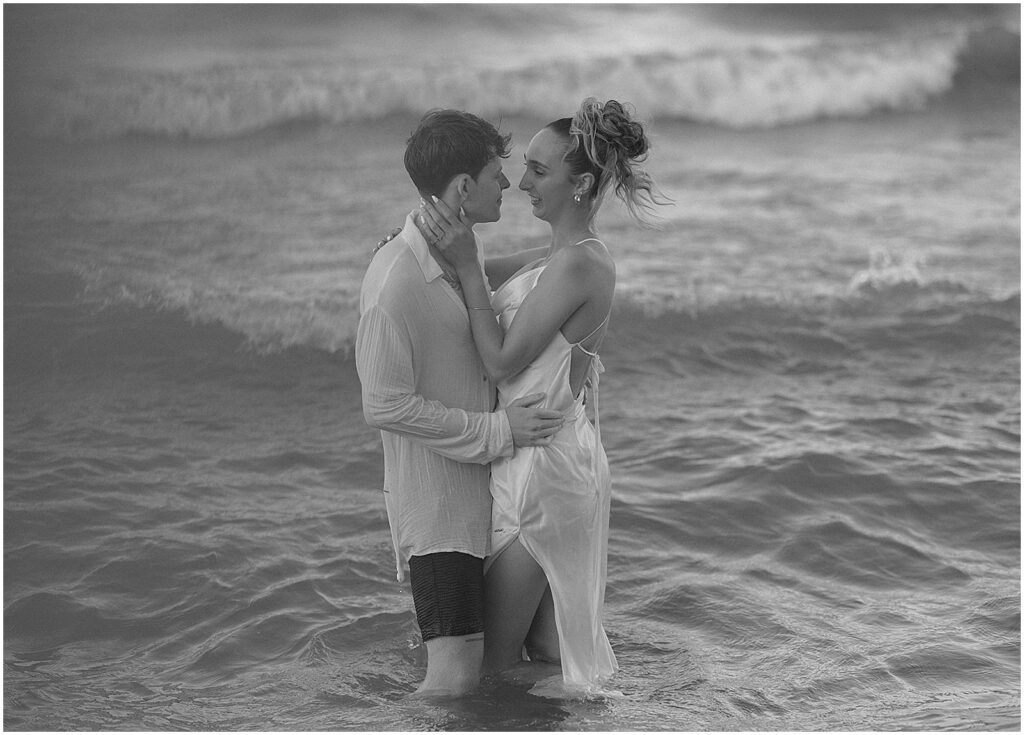 A bride and groom embrace in a lake during an elopement photography session at sunset.