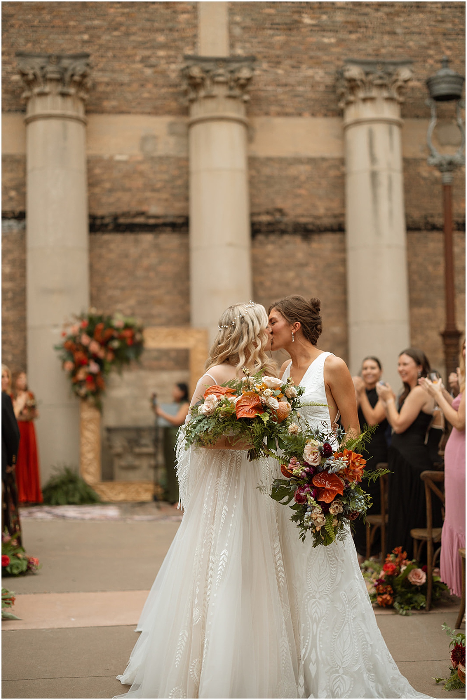 Two brides kiss at the end of their courtyard ceremony at an Artifact Events wedding.