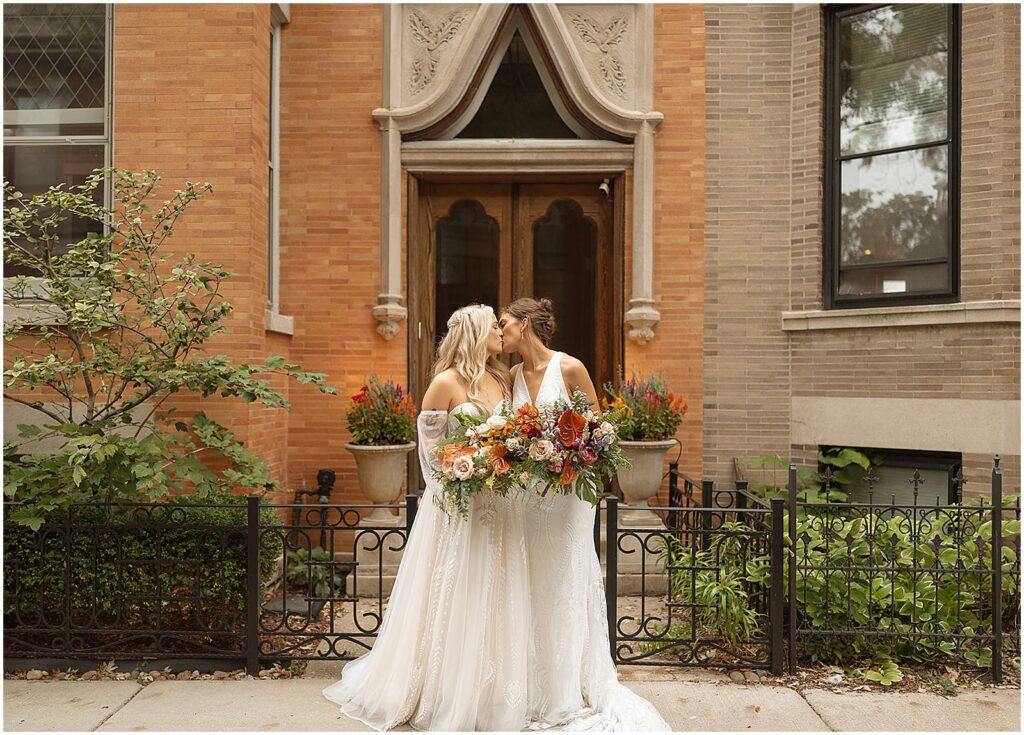 Two brides kiss in front of a historic row house in Chicago.