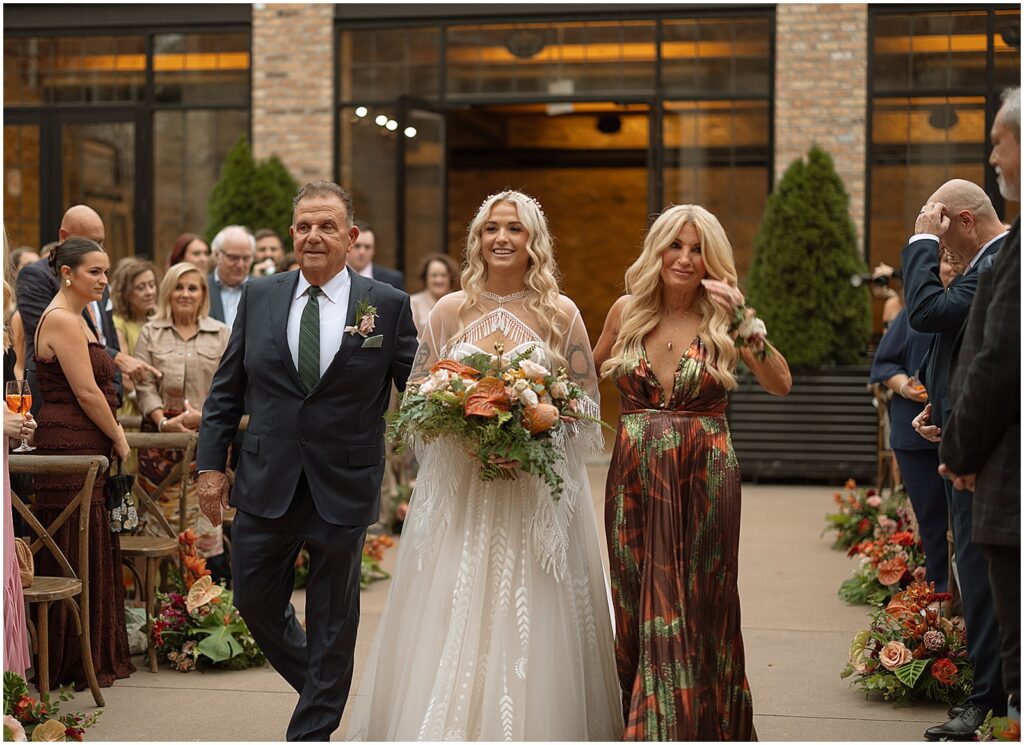 A bride's parents walk her up the aisle at her Chicago wedding.