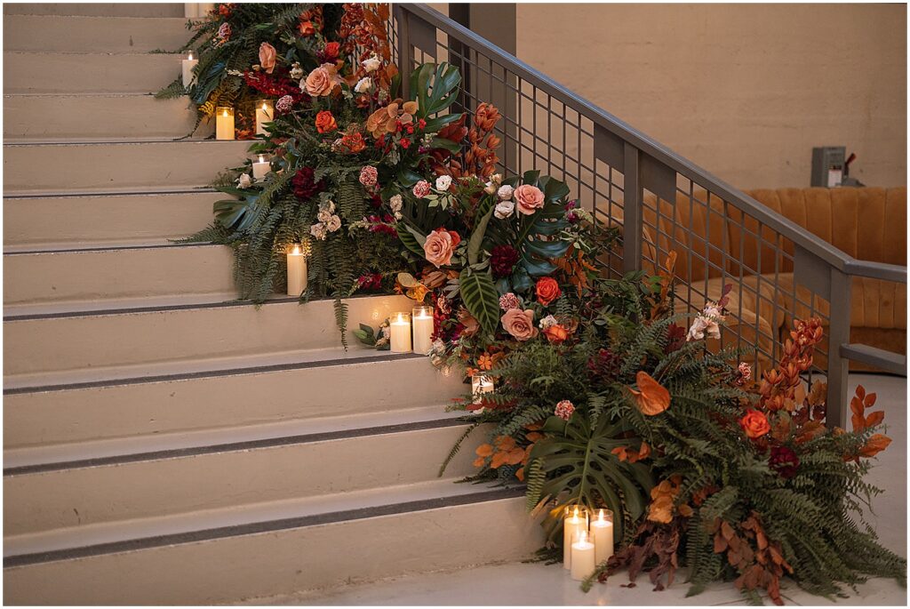 Flowers and candles line a staircase at an Artifact Events wedding.