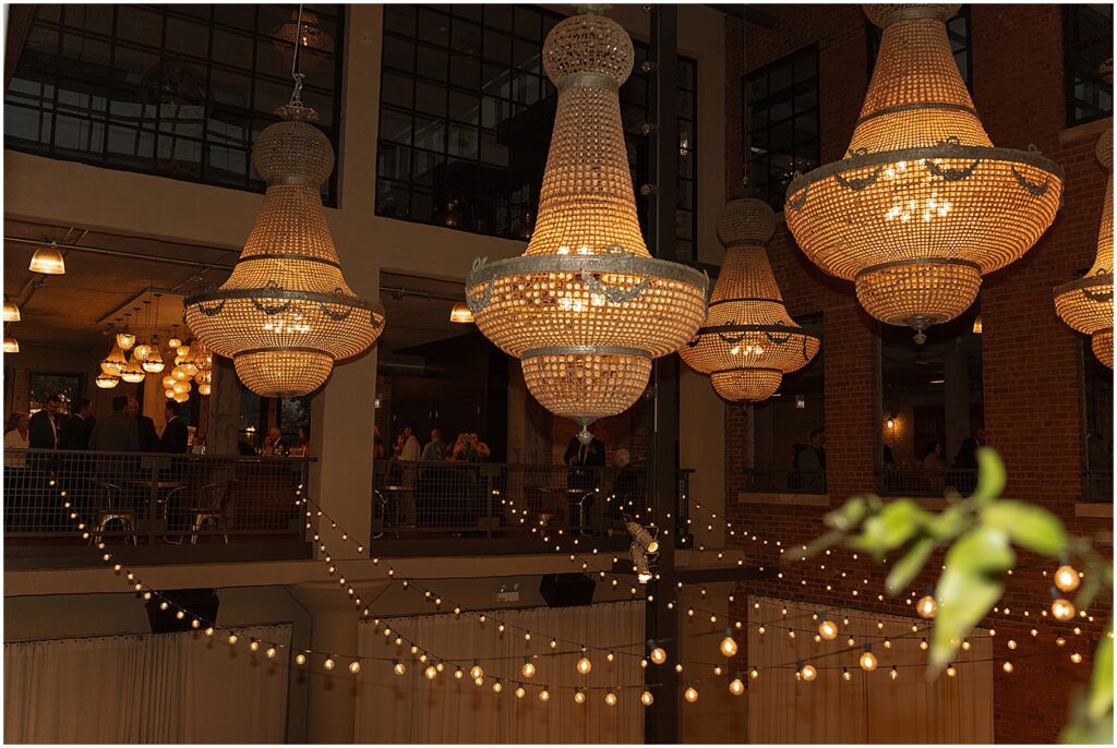 Chandeliers and strings of lights illuminate an atrium inside Artifact Events.