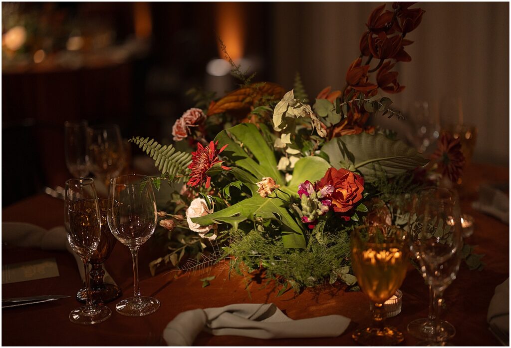 Flowers and ferns sit on a table.