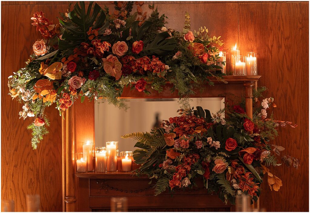 A floral installation and candles sit around a mirror at an Artifact Events wedding reception.