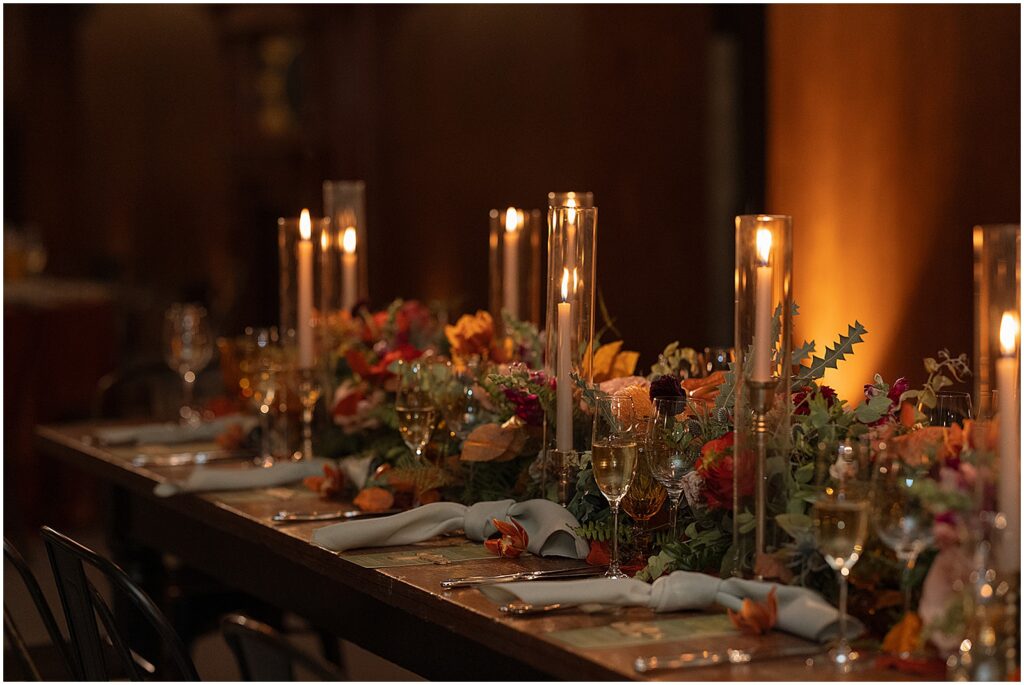 Candles and floral installations line a reception table at an Artifact Events wedding.