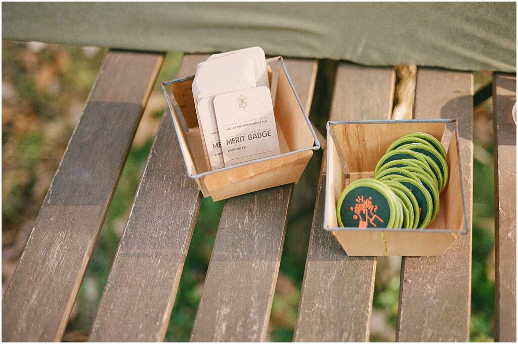 Merit badges sit in a basket on a picnic table.