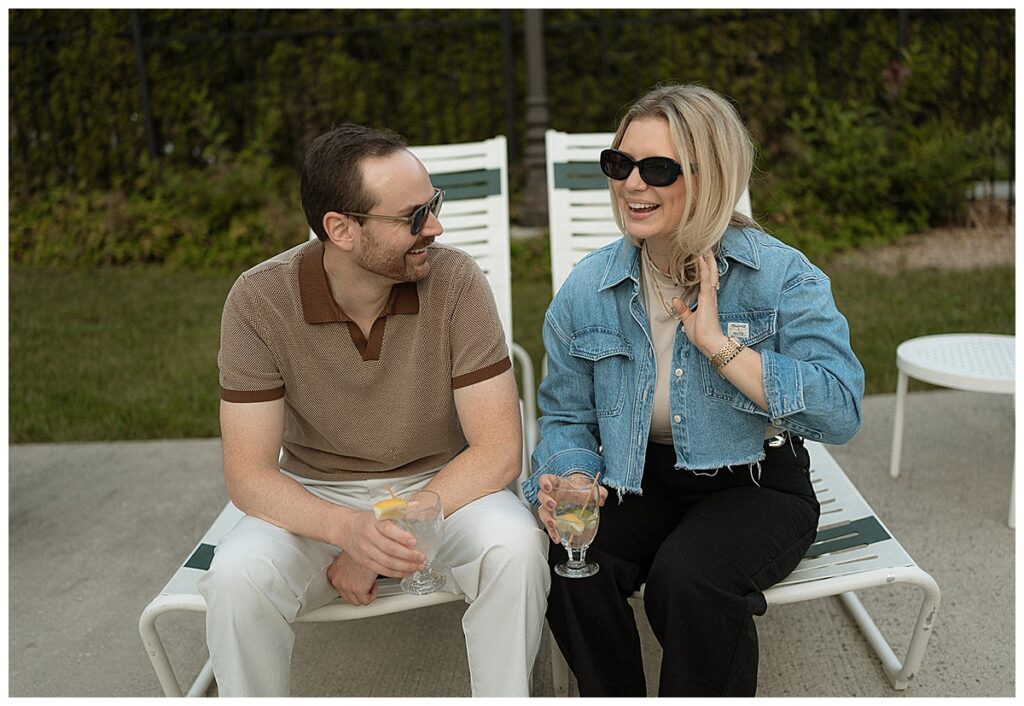a couple holding drinks poolside