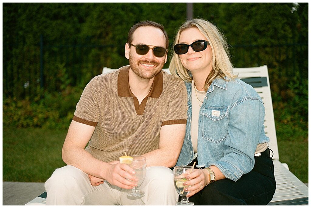 a couple holding drinks poolside