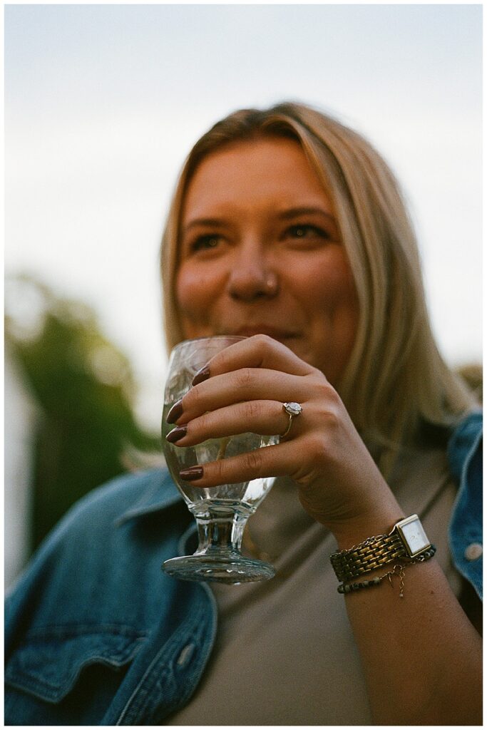 A woman holding a glass of water to show off her engagment ring